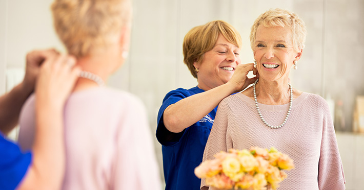 Nurse helping woman patient put on her jewelry 